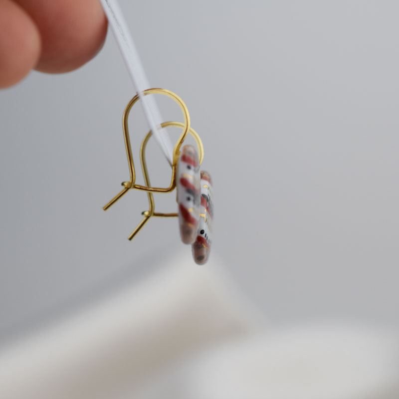 Porcelain hook earrings created and hand-painted by Vali Bondoc with high temperature ceramic dyes and colloidal gold