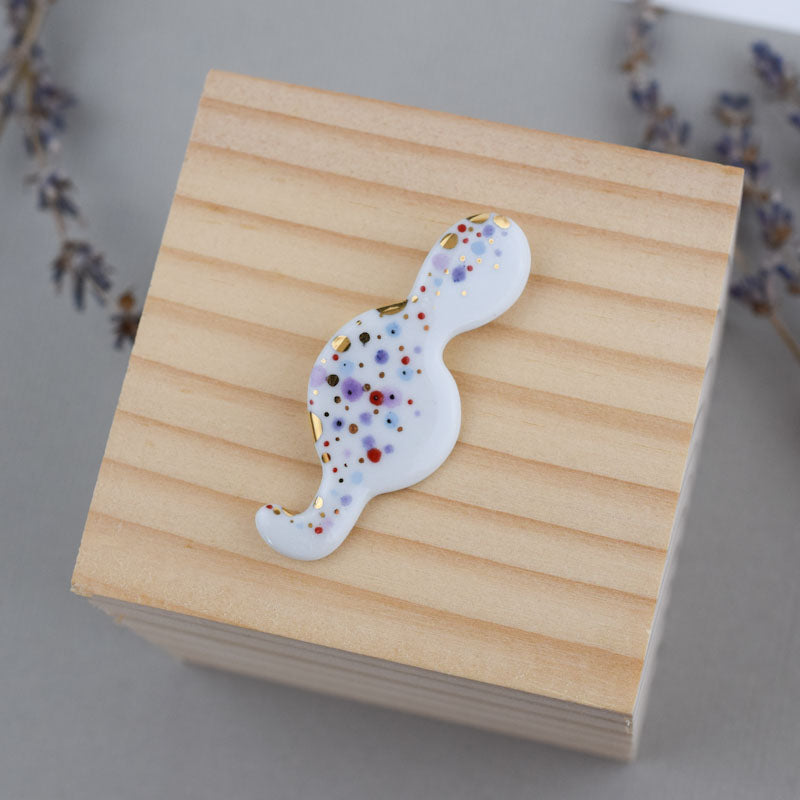 Porcelain brooch created and hand-painted by Vali Bondoc with high temperature ceramic dyes and colloidal gold.