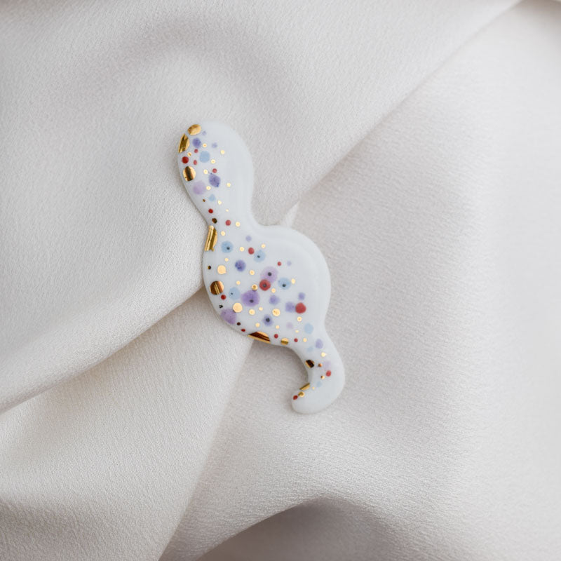 Porcelain brooch created and hand-painted by Vali Bondoc with high temperature ceramic dyes and colloidal gold.