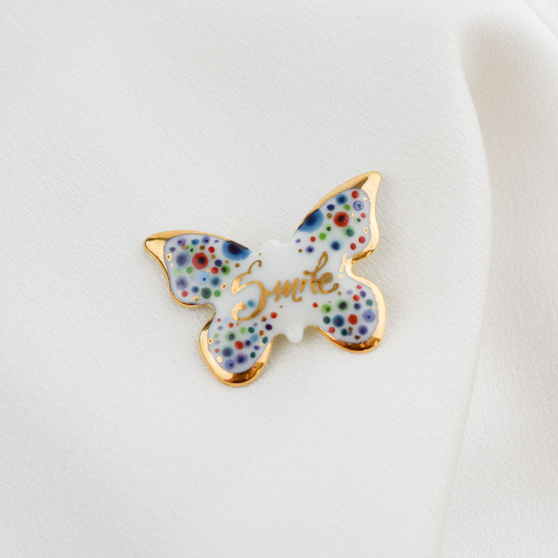Butterfly -Smile. Porcelain brooch created and hand-painted by Vali Bondoc with high temperature ceramic dyes and colloidal gold.