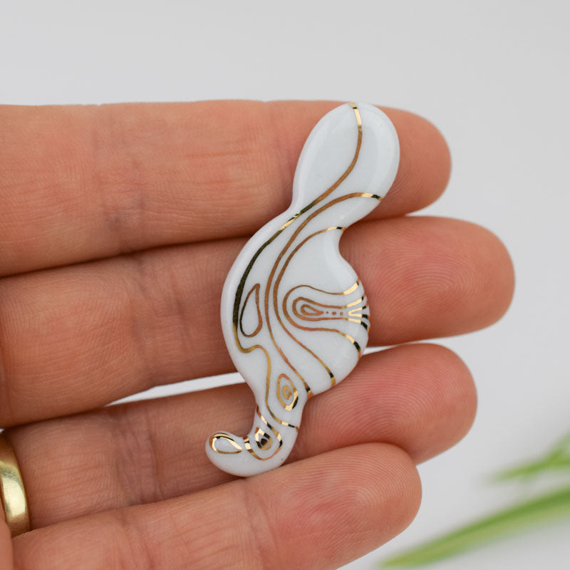 Porcelain brooch created and hand-painted by Vali Bondoc with high temperature ceramic dyes and colloidal gold.