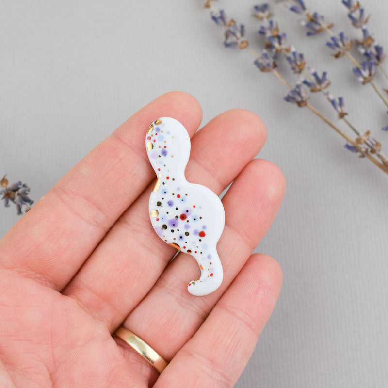Porcelain brooch created and hand-painted by Vali Bondoc with high temperature ceramic dyes and colloidal gold.